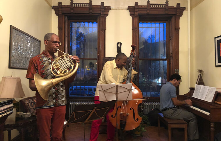 3 men playing various jazz instruments in what looks like a living room