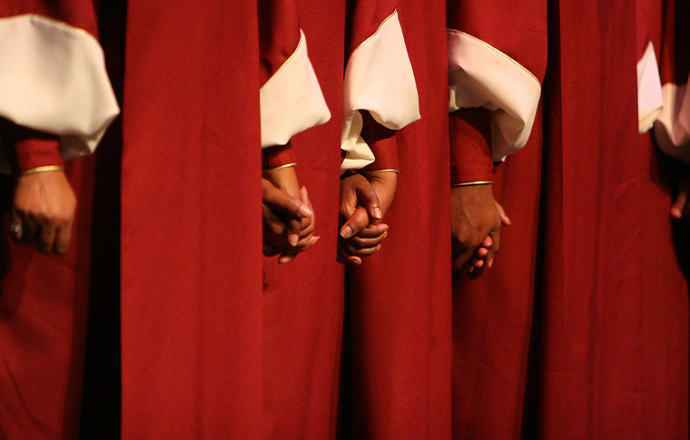 Cropped body picture of 3 people dressed in red and white choir robes